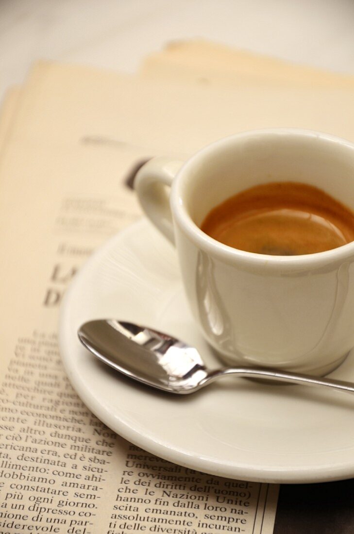 An espresso with a spoon on a newspaper