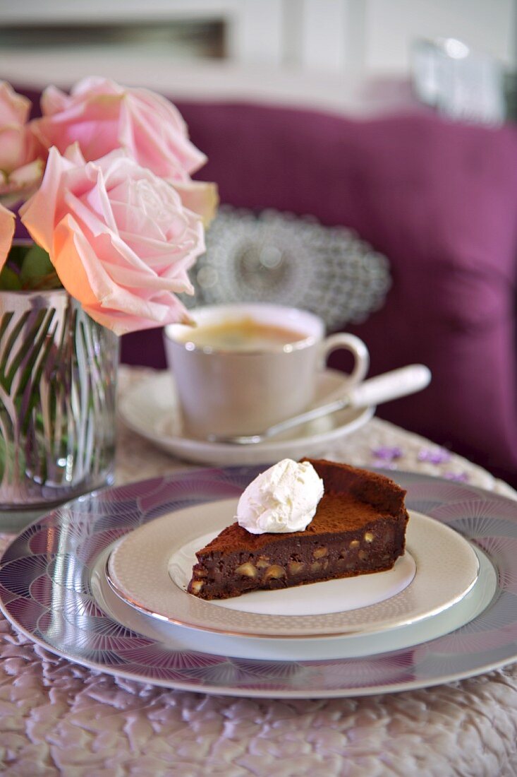 A slice of chocolate and hazelnut cake topped with cream