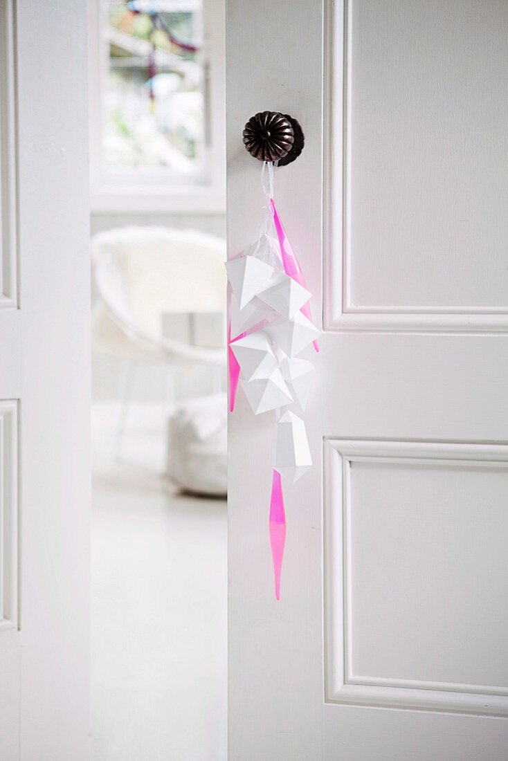weiße, gefaltete Papieranhänger und pinkfarbene Streifen am Türknauf
