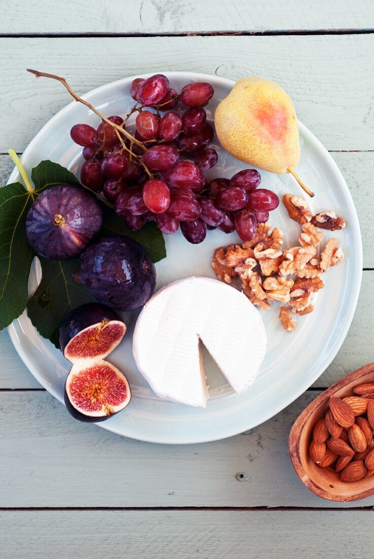 Brie with figs, grapes, pears and walnuts on a plate
