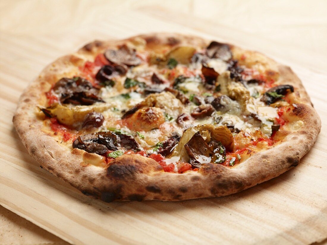 A four seasons pizza baked in a wood-fired oven topped with mushrooms, artichokes and olives