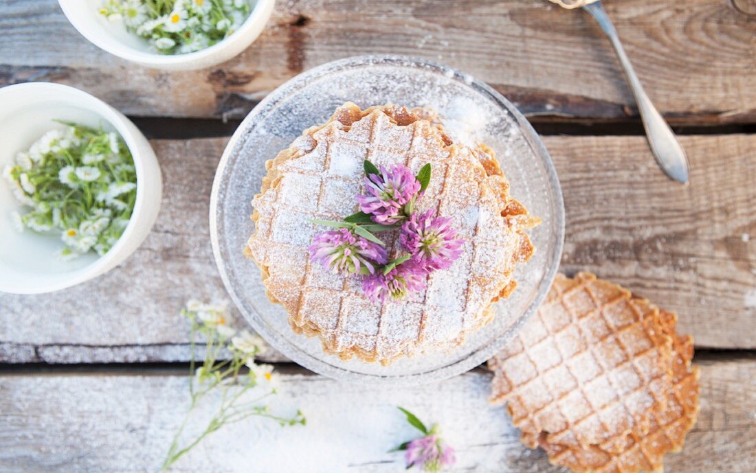 Homemade nut waffles with icing sugar and wild flowers (seen from above)