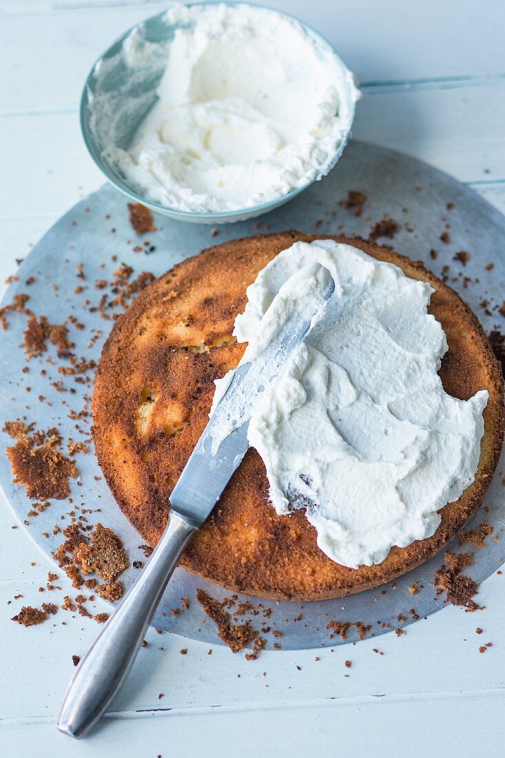 Sponge cake base being spread with cream