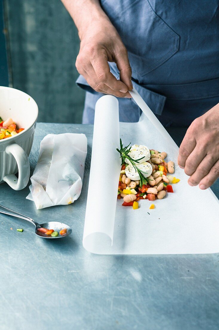 A bean medley being wrapped in parchment paper with goat's cream cheese