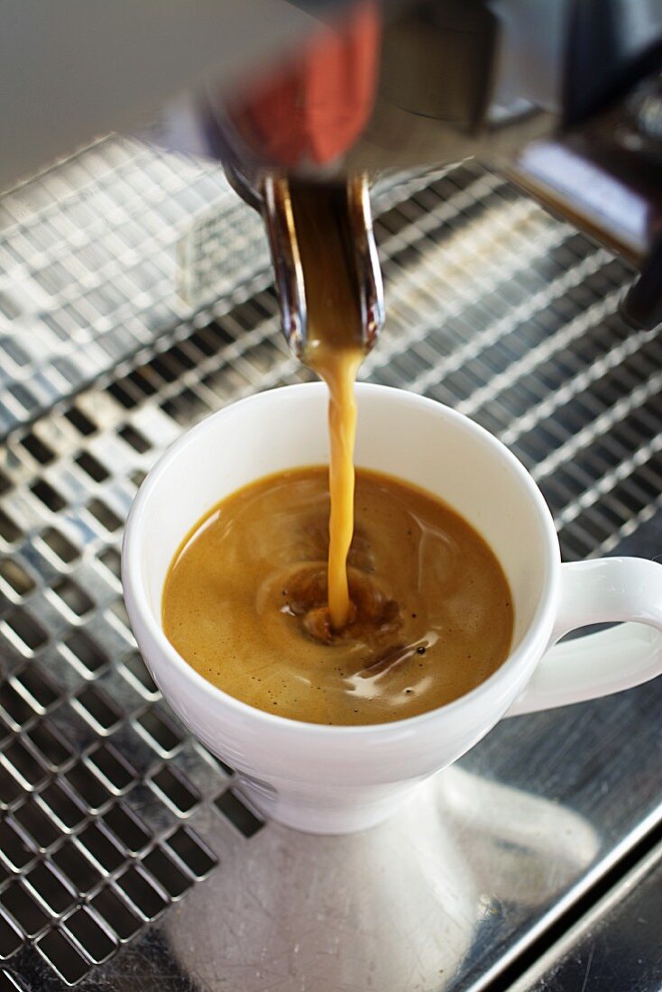 Kaffee fliesst von einer Kaffeemaschine in eine Espressotasse