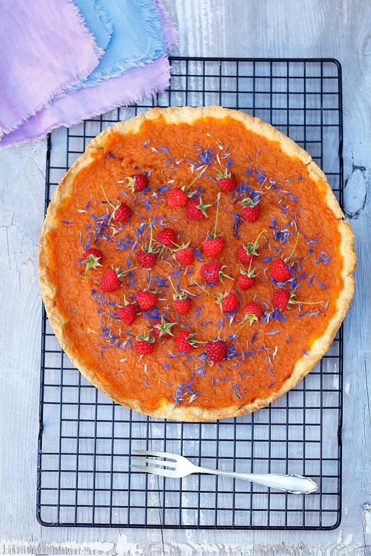 Pumpkin tart with orange marmalade, raspberries and corn flowers