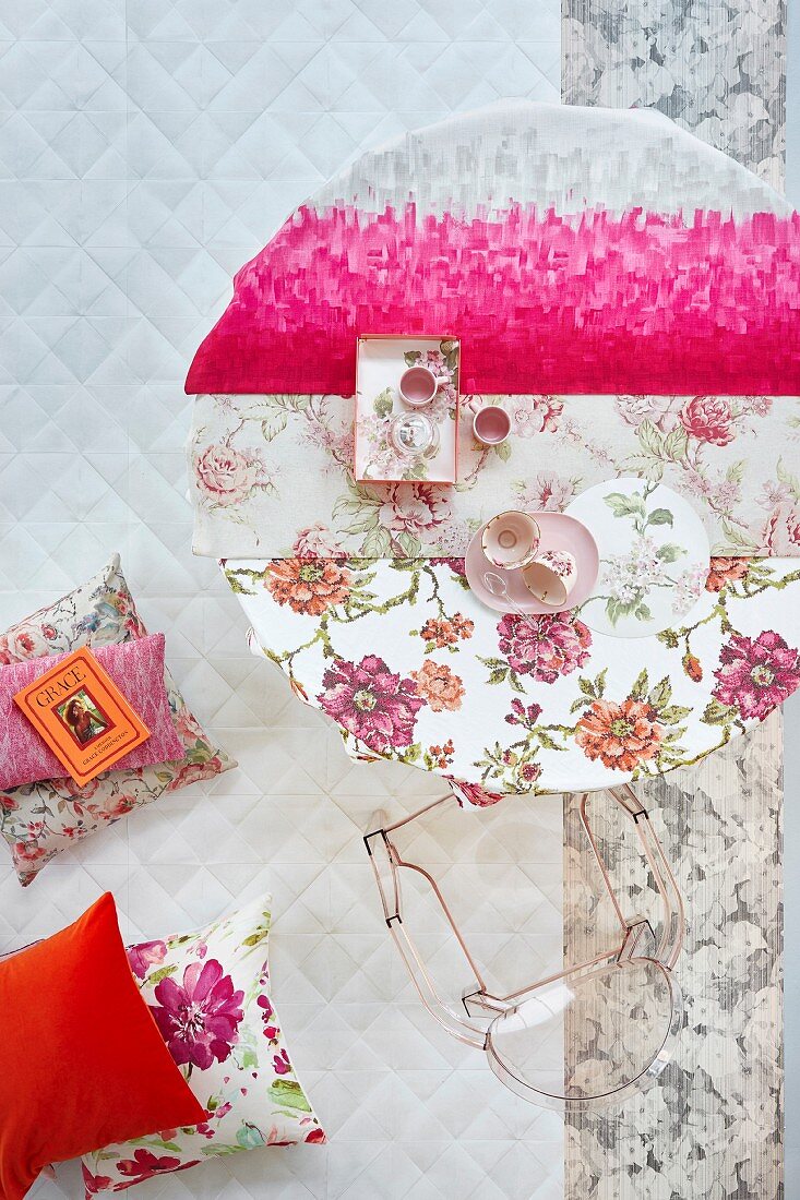 Kräftiges Pink als moderner Akzent zu Decken mit femininen Blütenmustern auf einem rundem Tisch