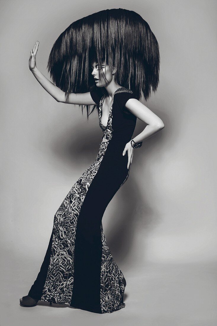 A woman wearing a long evening dress with an outlandish hairstyle (black-and-white shot)