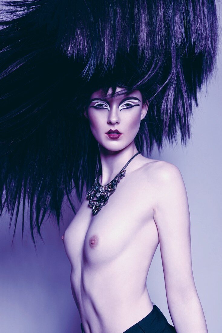 A topless woman wearing a necklace with an outlandish hairstyle