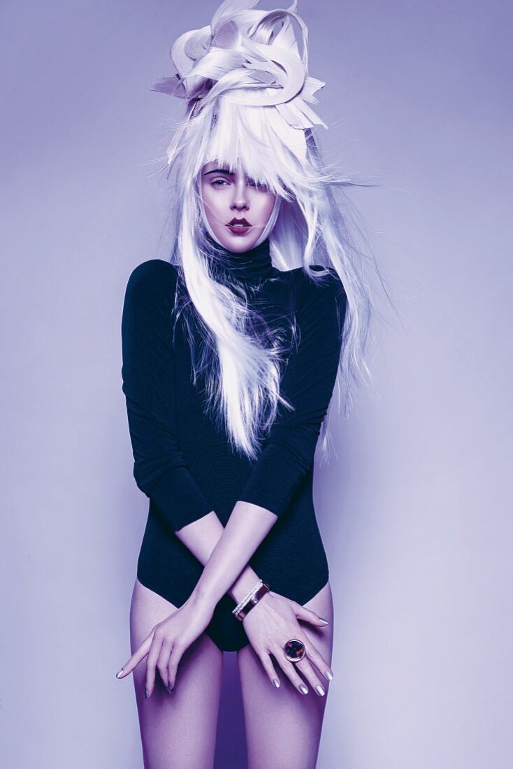 A woman wearing a dark, long-sleeved bodysuit with an unusual wig