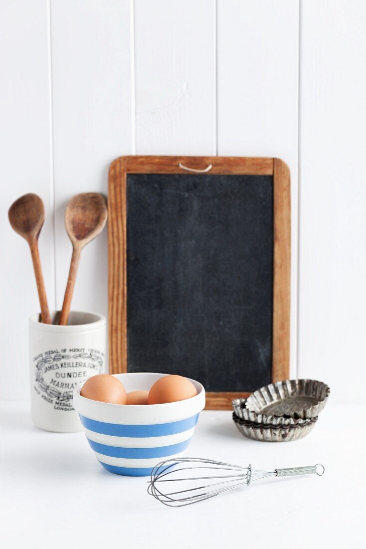 Eggs, a whisk, baking tins, wooden spoons and a blackboard