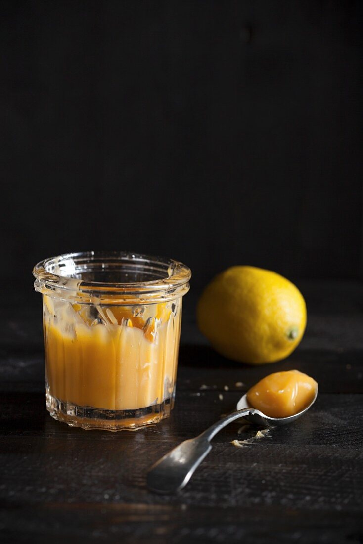 A jar of lemon curd on a dark wooden table