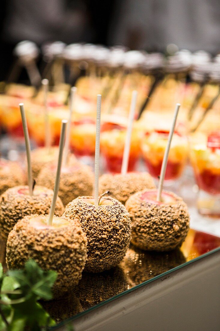 Chocolate and nut-coated apples and glasses of fruit cocktail