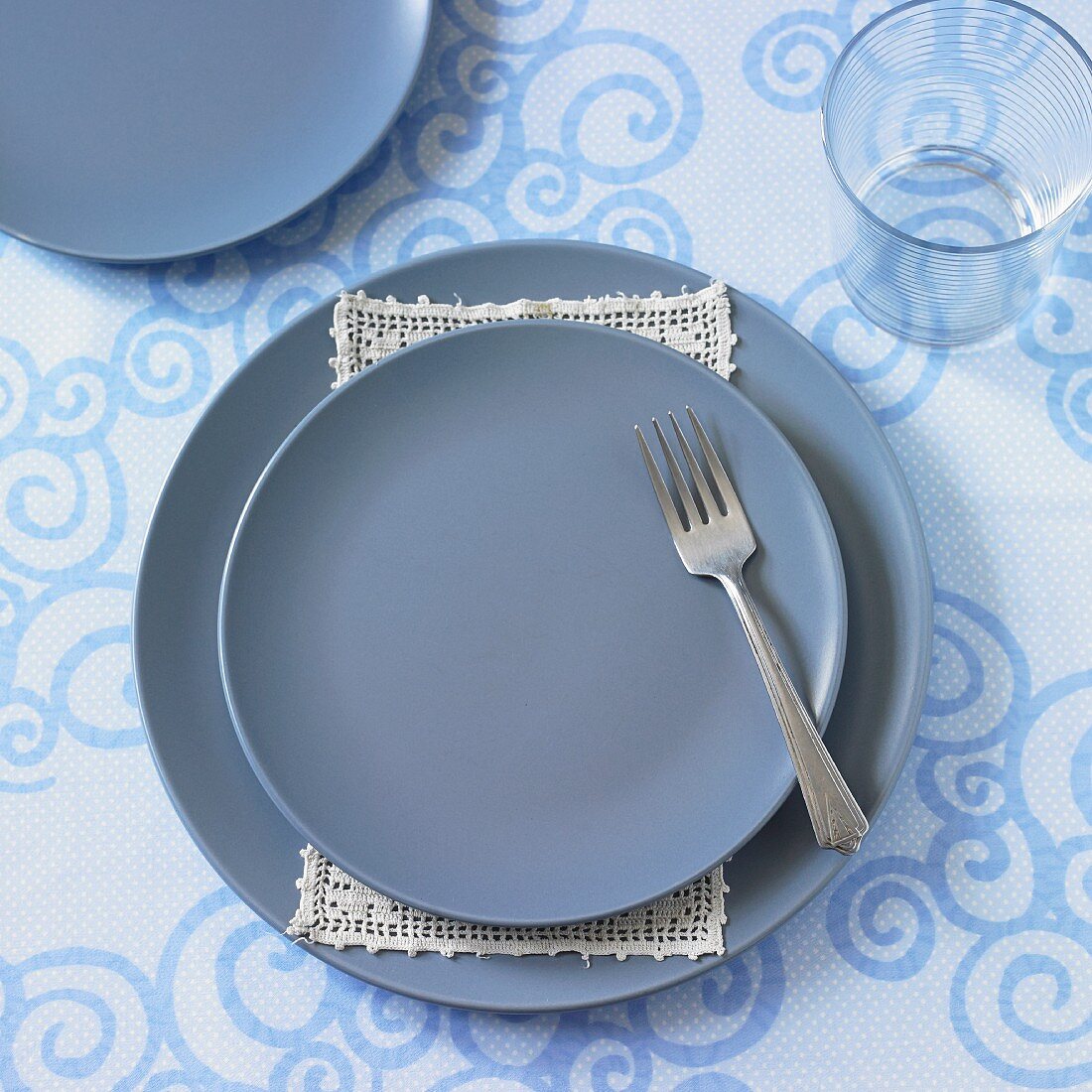 A place setting with blue plates and a fork (seen from above)
