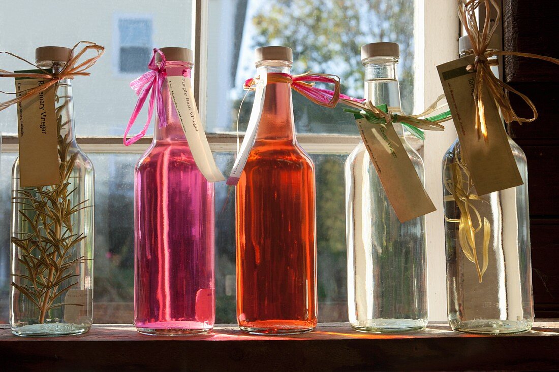 Homemade flavoured vinegar in bottles on a window sill