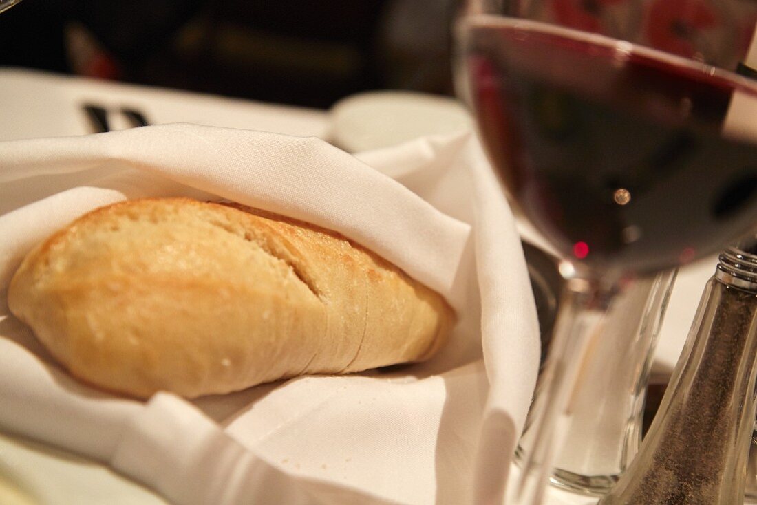 Weißbrot, in Serviette eingeschlagen, und ein Glas Rotwein