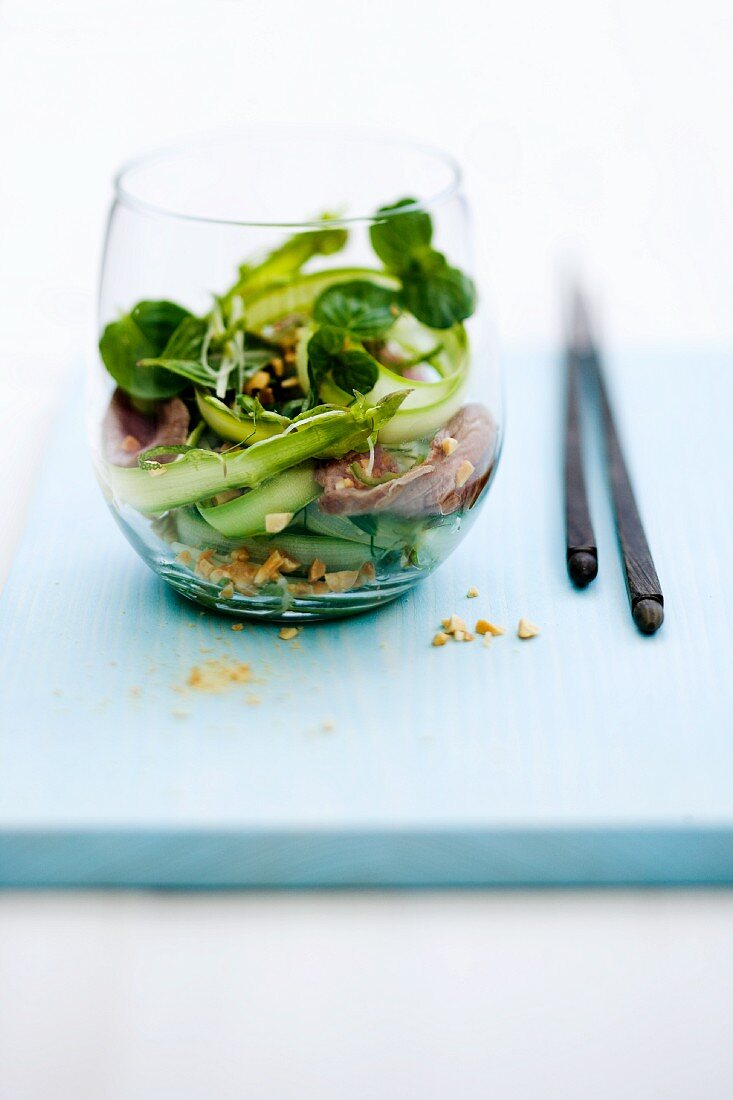 Spicy-sour asparagus and lamb fillet salad with peanuts and peppermint in a glass