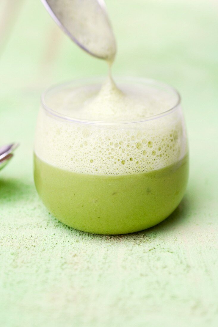 Pea and Thai curry soup with mint foam in a glass