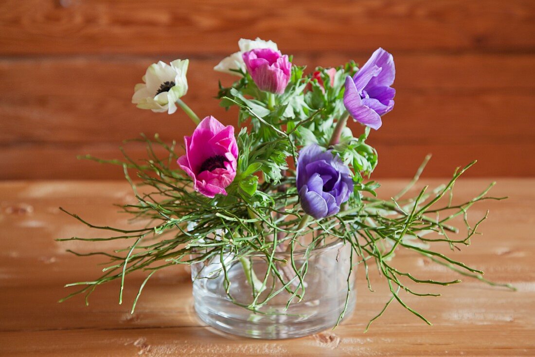 Anemones and bilberry stems in glass bowl