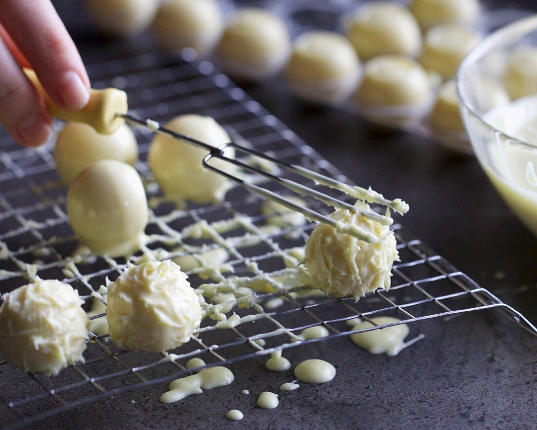 White truffle pralines being decorated with a praline fork