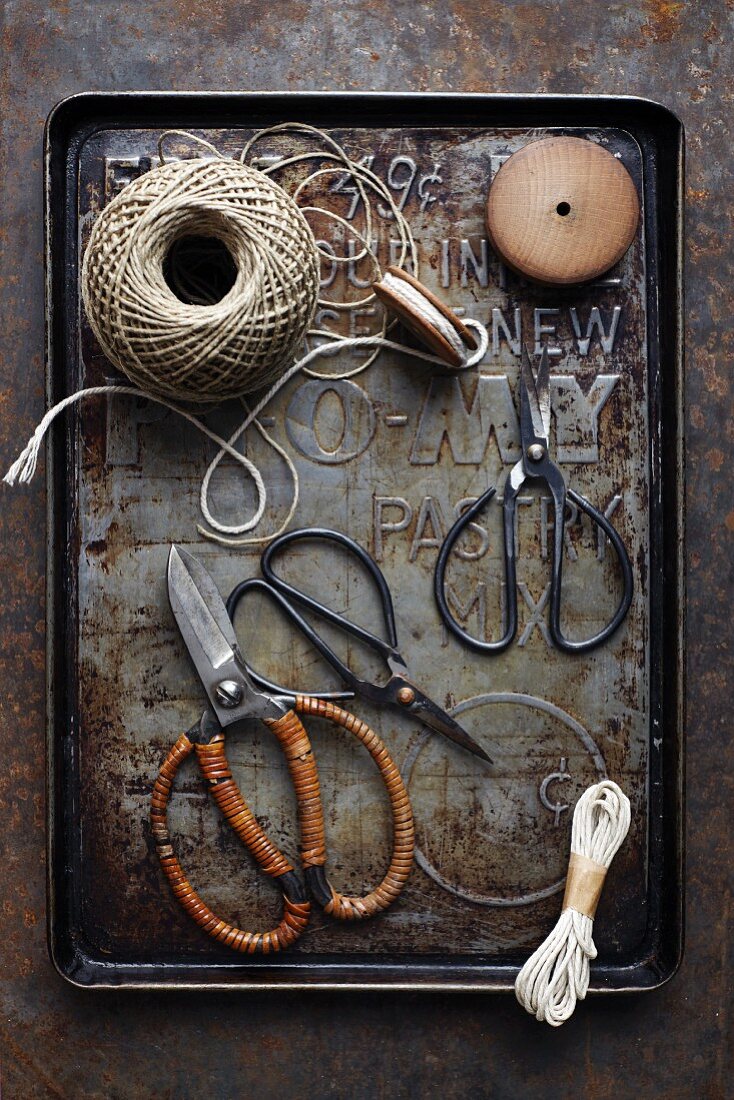 Various pairs of old scissors and kitchen twine on a baking tray