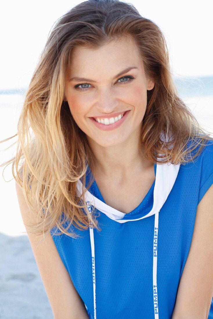 A young woman on a beach wearing a blue top