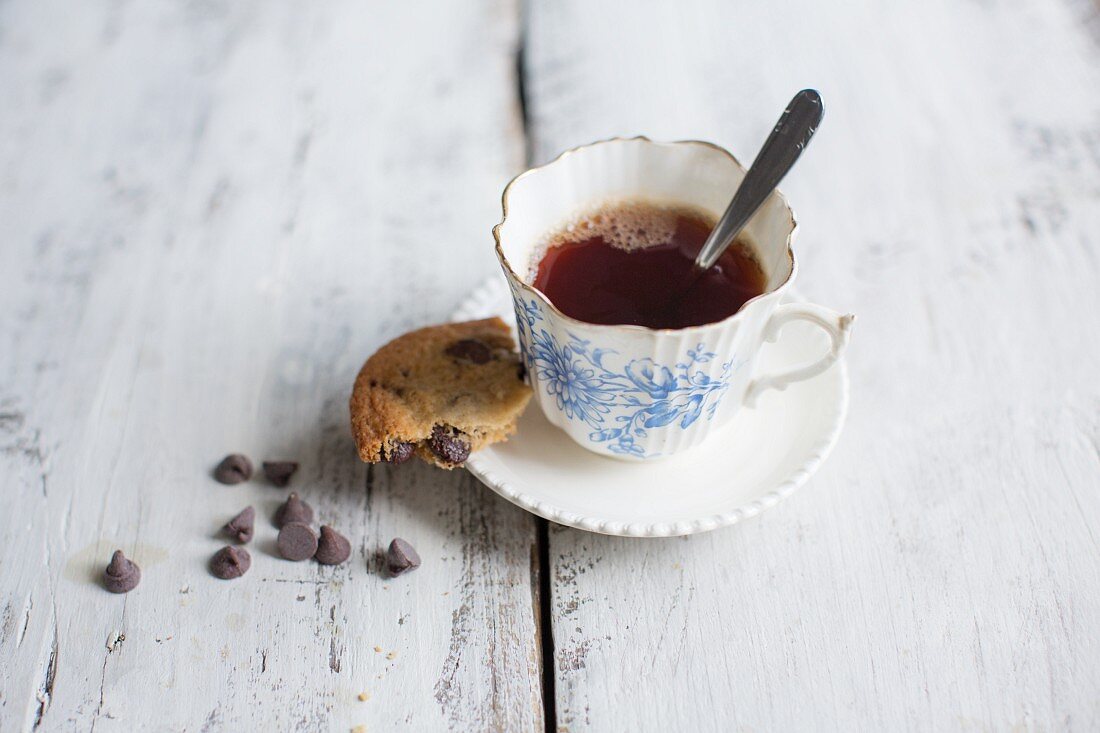 A chocolate chip cookie with a cup of tea