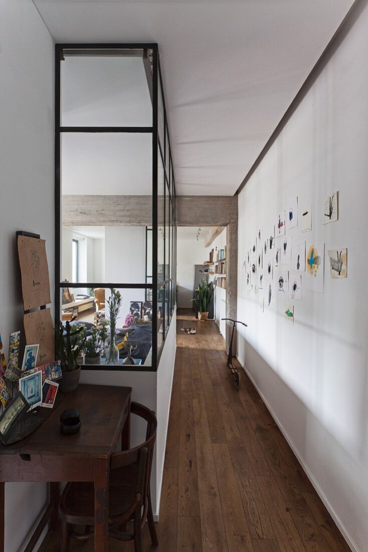 Desk in narrow hallway next to glazing glass wall