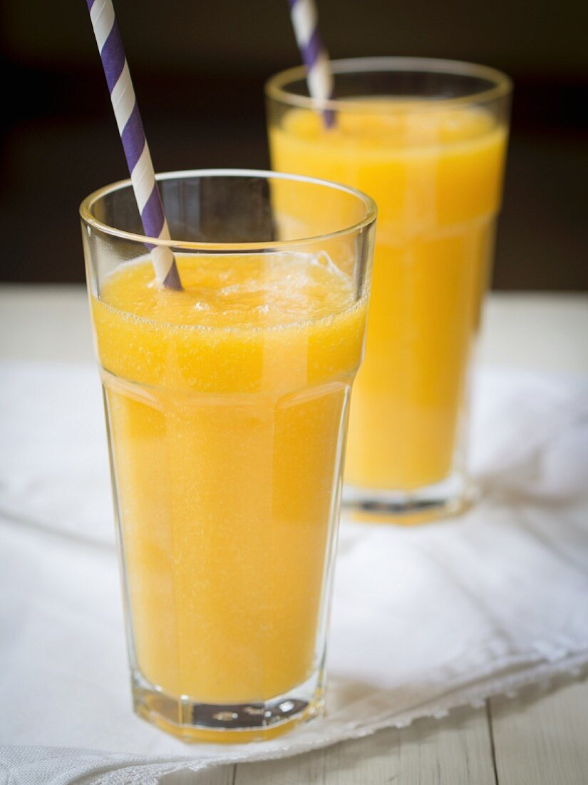 Yellow exotic fruit smoothies in glasses with straws