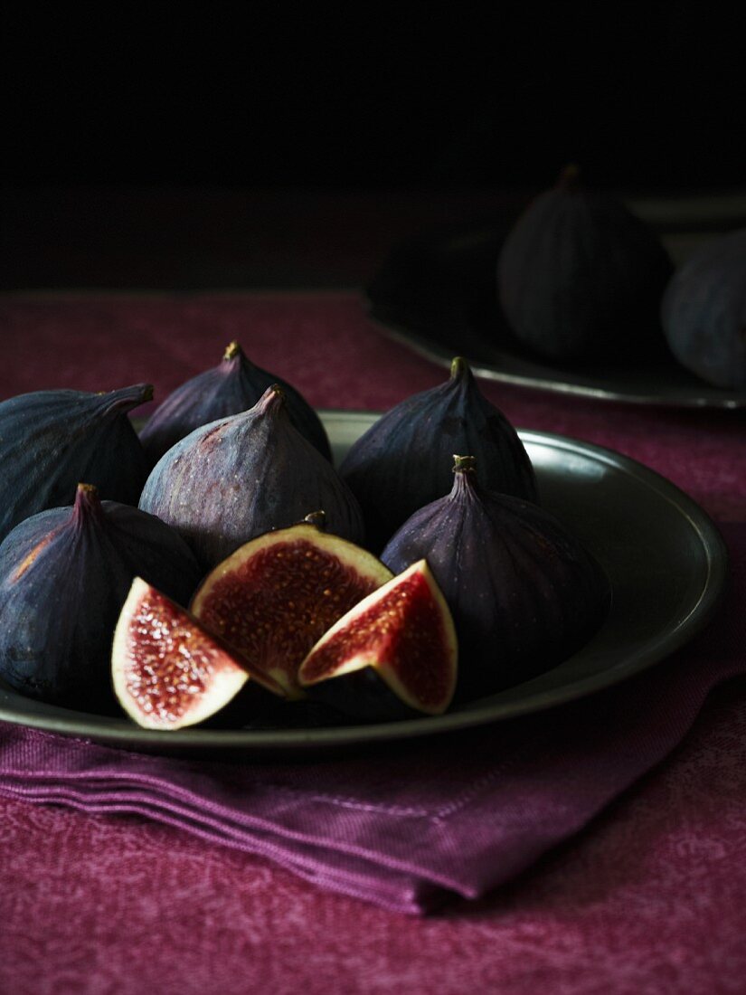 Fresh red figs on a plate, one sliced
