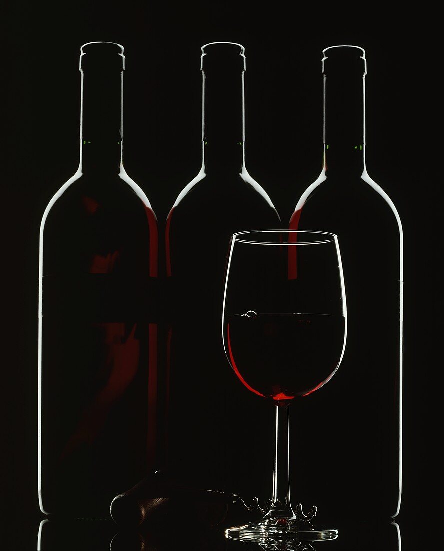 Silhouette of three red wine bottles and one red wine glass