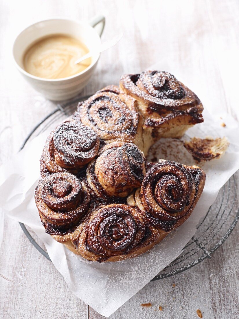 Poppyseed buns with plum jam and icing sugar served with a cup of coffee