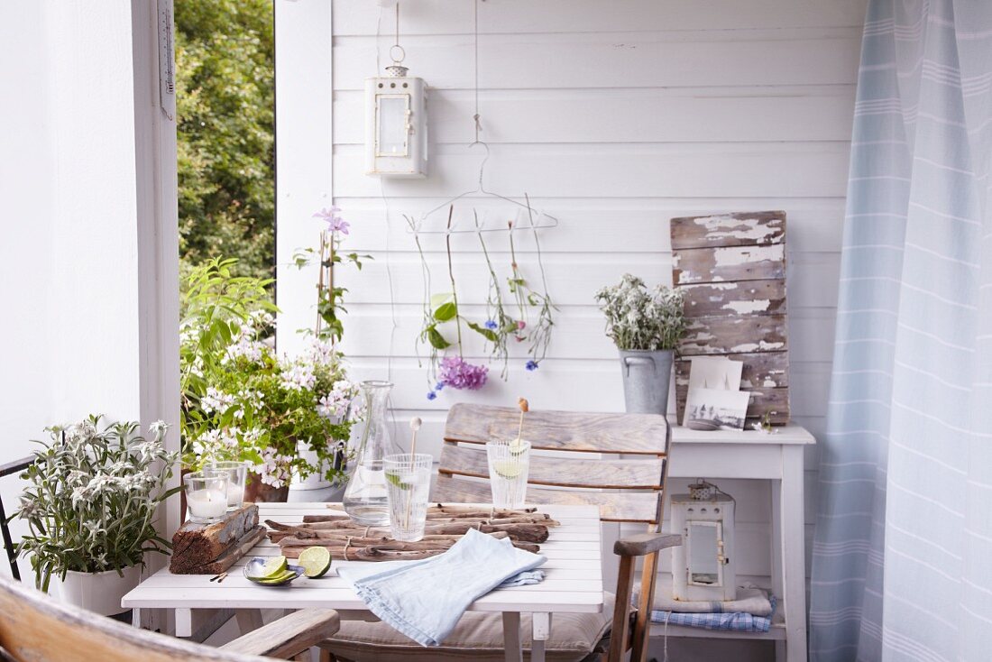 Terrasse mit Tisch sommerlich dekoriert mit Blumen und Fundstücken aus der Natur