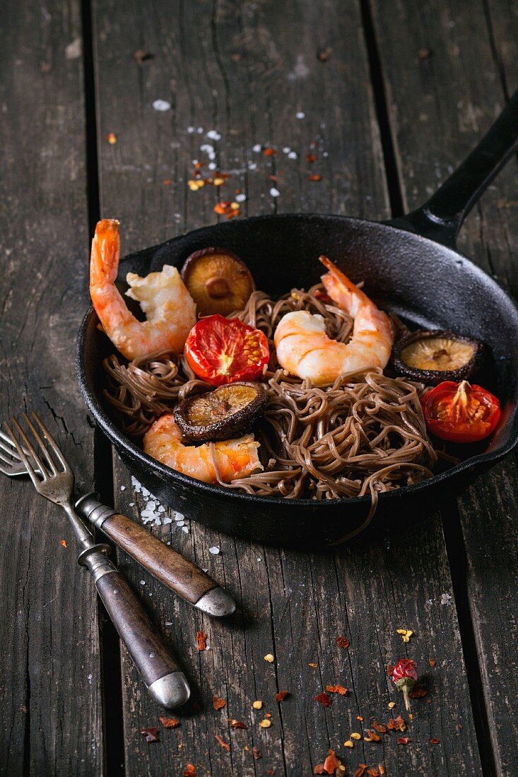 Prawns with soba noodles, mushrooms and tomatoes in a pan
