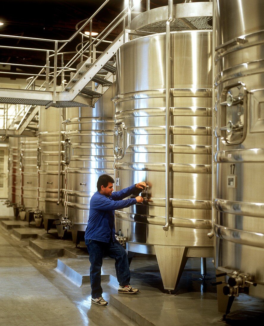 Arbeiter füllt Glas aus Tank im Château Latour, Medoc, France