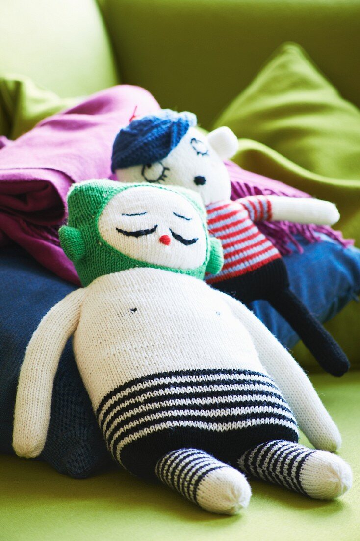Two knitted dolls on blue cushion