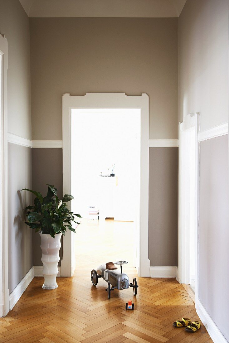 Flurbereich mit grau getönten Wänden, weißen Türrahmen und Fischgrätparkett