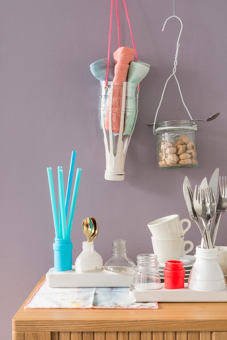 Plastic bottles and jam jars hanging on the wall being used as holders for kitchen utensils