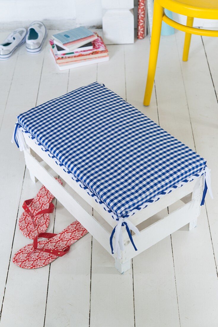 A white footstool with a homemade, checked cover