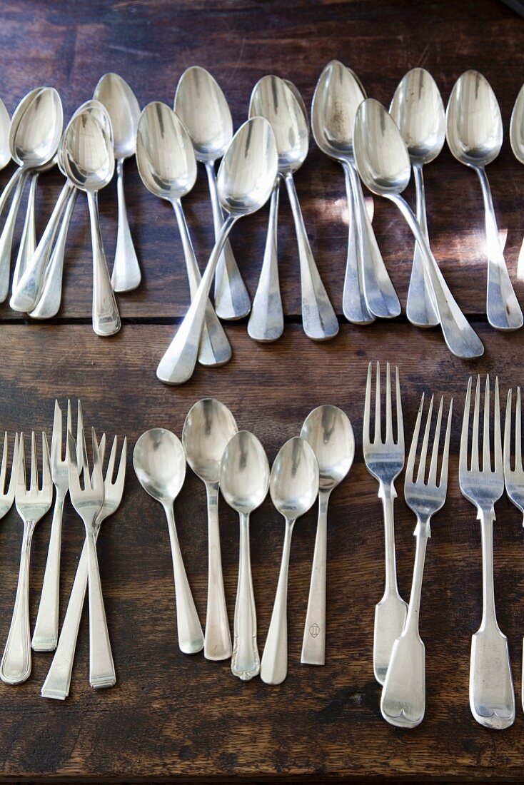 Silver cutlery lined up on rustic wooden table