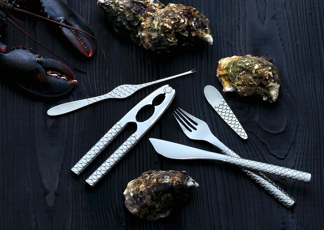 Cutlery for fish and seafood next to oysters and lobster