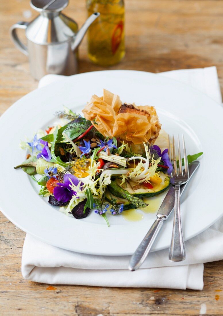 A goat's cheese filo pastry served with salad with herbs and edible flowers