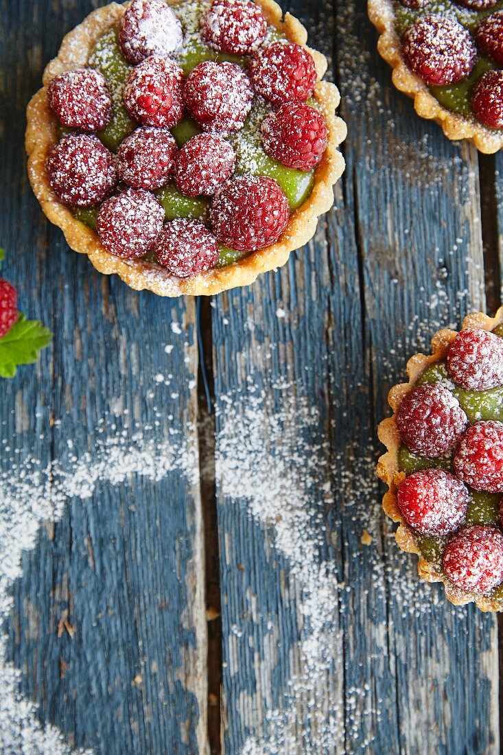 Mini raspberry and matcha tartlets dusted with icing sugar