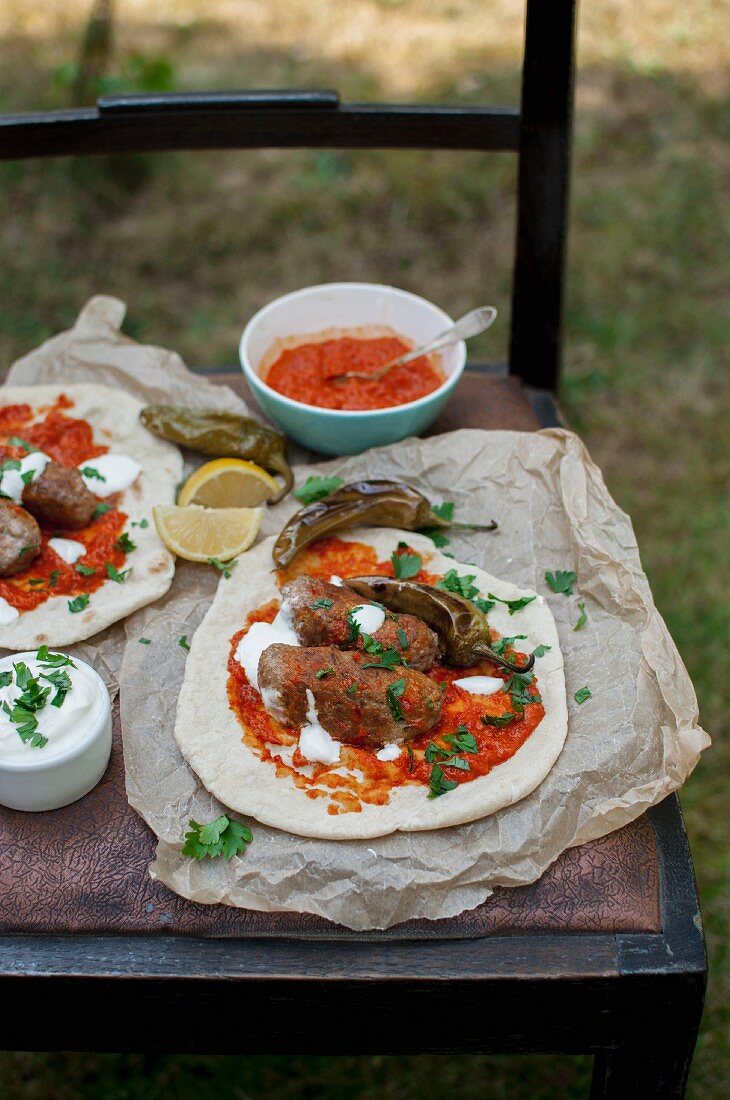 Cevapcici, on unleavened bread with ajvar, yoghurt, fresh parsley, roasted green chillis and lemon wedges