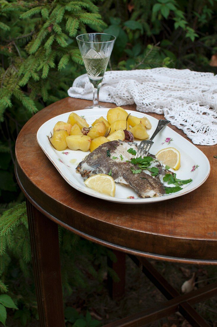 Fried plaice with garlic and rosemary potatoes, lemons and fresh parsley