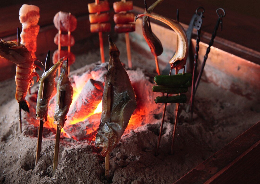 Barbecue skewers being grilled at a table over a coal fire (Robatayaki, Japan)