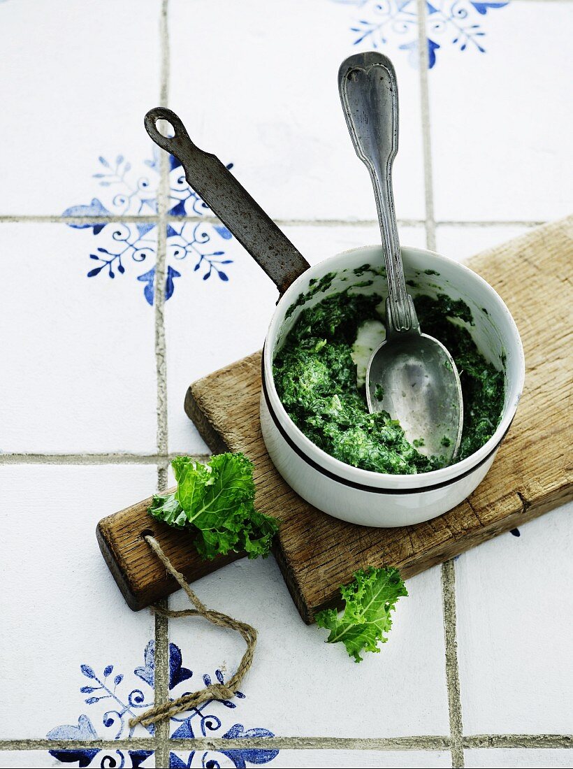 Kale in a saucepan on a wooden board