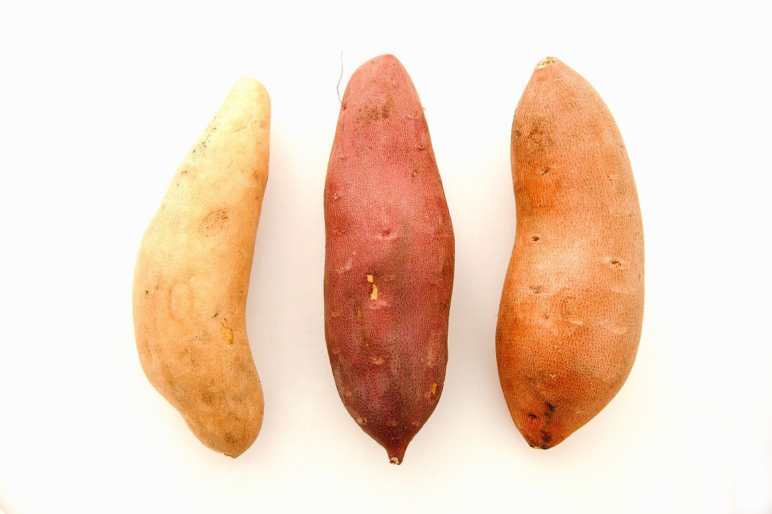 Drei verschiedene Süsskartoffeln vor weißem Hintergrund