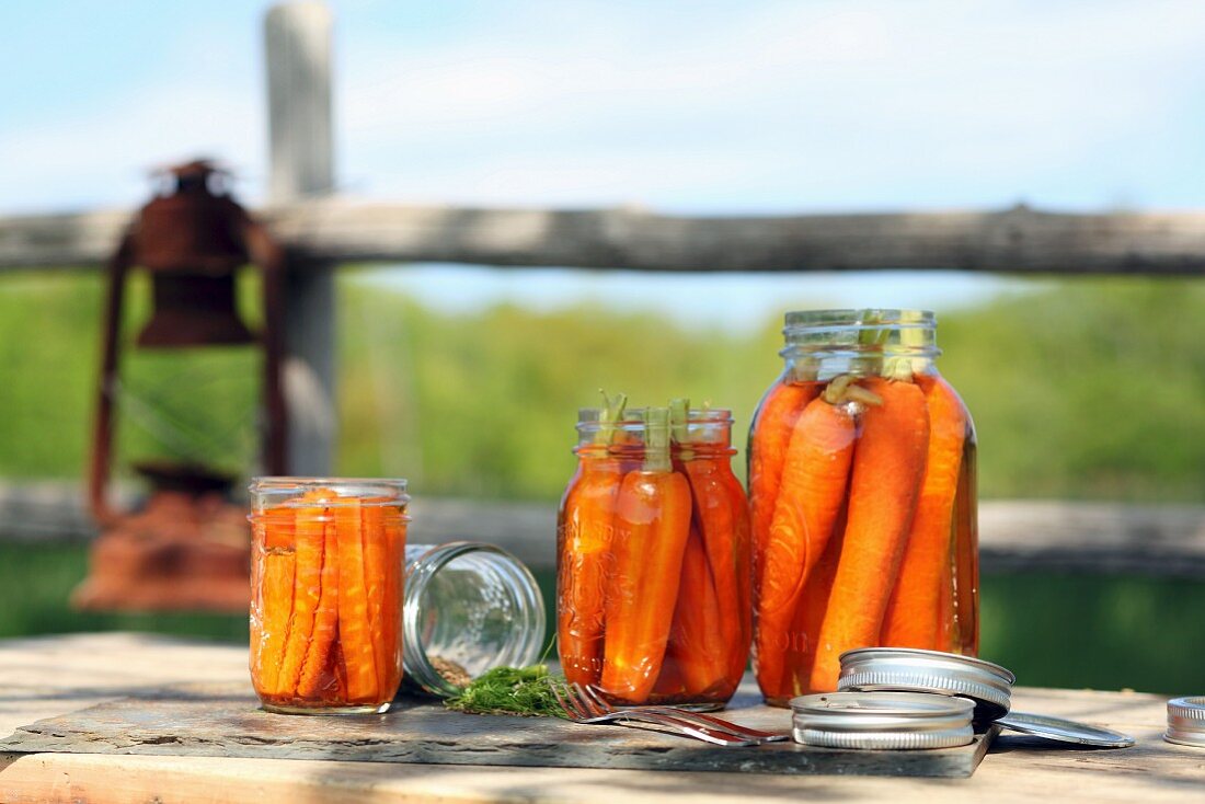 Karotten in Einmachgläsern auf Tisch im Freien
