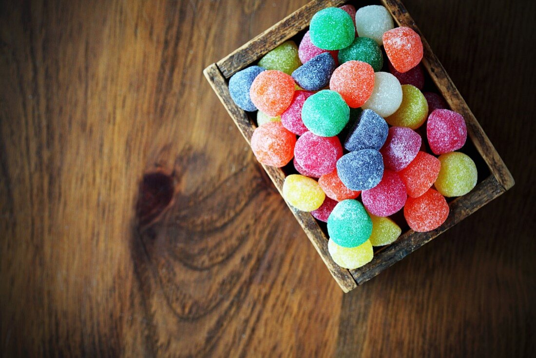 Colourful jelly sweets in a wooden crate (seen from above)